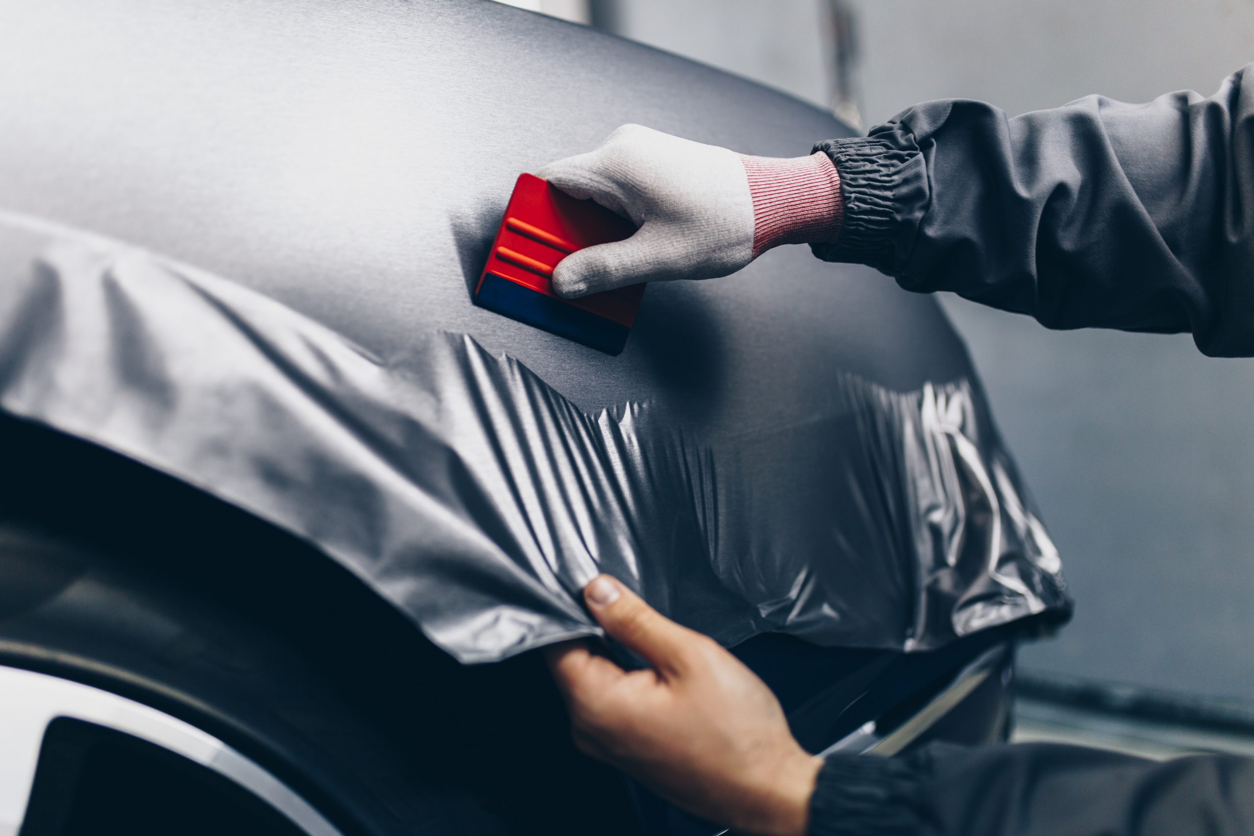 Car wrapping specialist putting vinyl foil or film on car. Selec